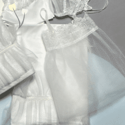 Λαδόπανο βάπτισης σε λευκές αποχρώσεις, με δαντέλα, τούλι πουά και διακοσμητικές λεπτομέρειες.